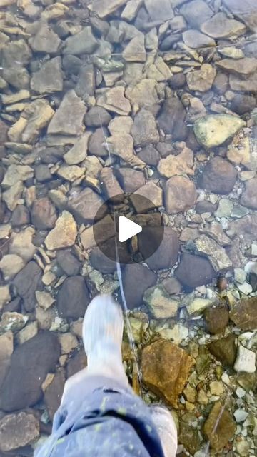 a person standing on top of a river next to rocks