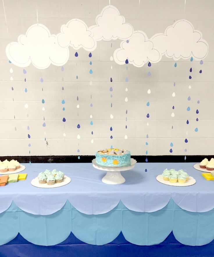 a table topped with cakes and cupcakes under a cloudy blue sky above them