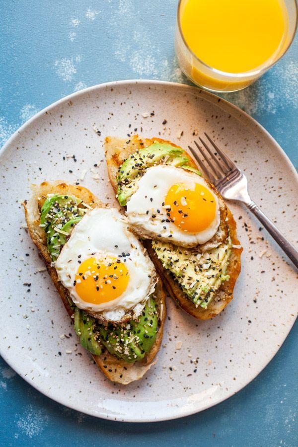 an egg and avocado sandwich on toast with orange slices