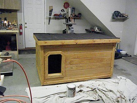 a dog house built into the side of a wall in a room that is being worked on