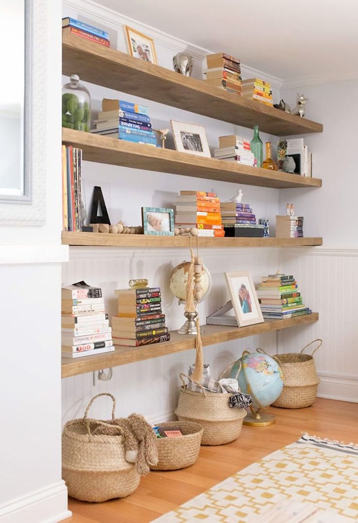 the bookshelves are full of books and baskets on each shelf in this room