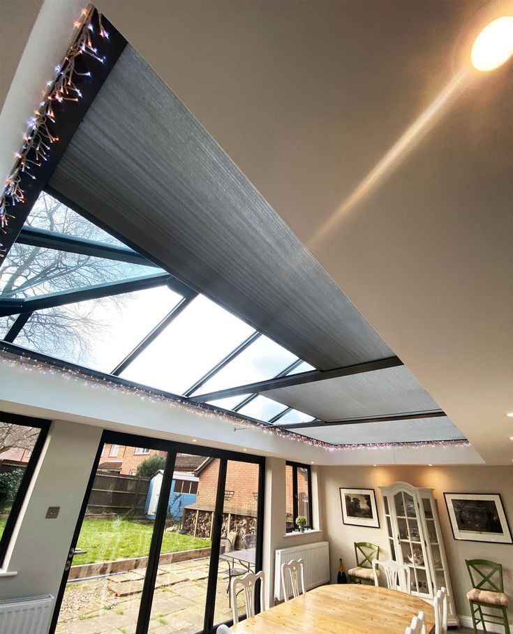 a dining room table and chairs under a skylight with lights on the ceiling above it