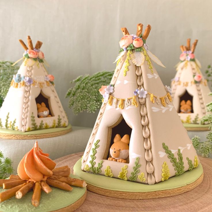 three cakes made to look like teepees with animals in the tent on top