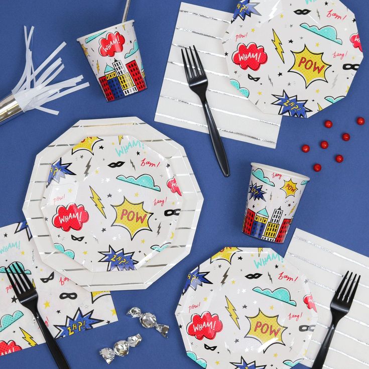 a table set up with paper plates, forks and candy bar wrappers in the shape of comic characters