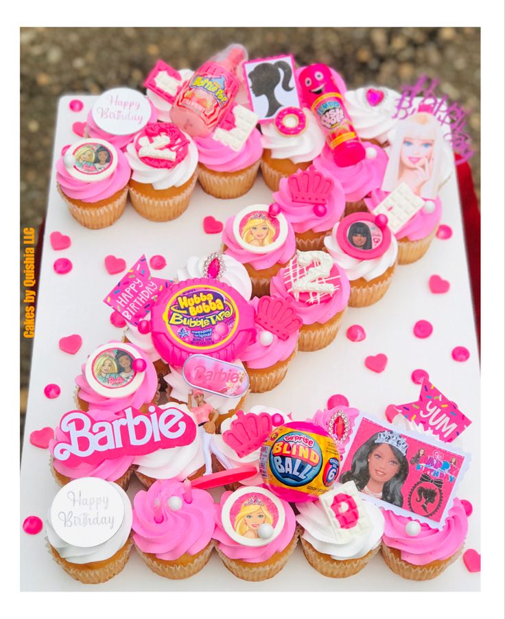 a table topped with lots of cupcakes covered in pink frosting