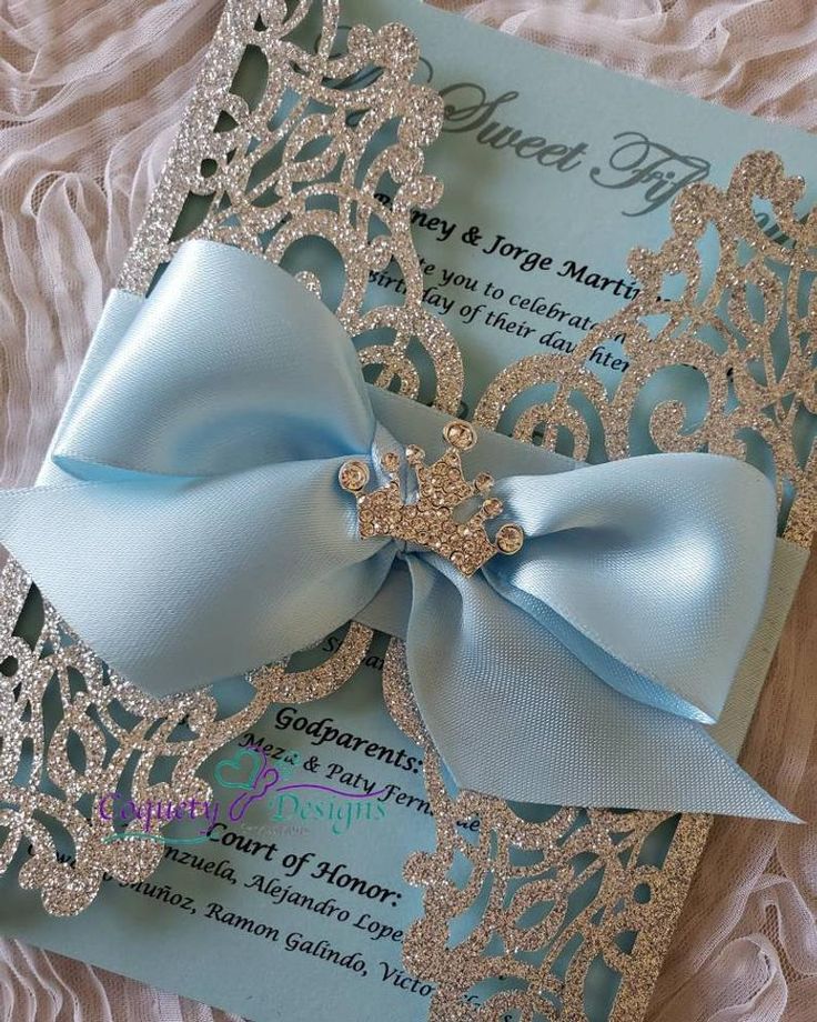 a blue and silver wedding card with a large bow on the front, sitting on a bed