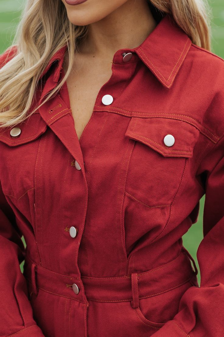 Crafted from 100% cotton, this Red Denim Romper exudes a classic & sophisticated charm, perfect for any sports event! Featuring a collared v neckline and functional buttons, this romper also boasts both chest and front/back pockets for convenience. The button zip fly closure and buttoned cuffs add a touch of elegance to this versatile piece. Simply style it with your favorite knee high boots and then add some matching accessories for an elevated chic look! Trendy Collared Jumpsuits And Rompers With Button Closure, Collared Denim Jumpsuit With Button Closure, Relaxed Fit Cotton Collared Jumpsuit, Trendy Collared Cotton Jumpsuits And Rompers, Trendy Cotton Collared Jumpsuits And Rompers, Casual Collared Denim Jumpsuit With Button Closure, Spring Trendy Collared Denim Jumpsuit, Trendy Spring Collared Denim Jumpsuit, Button-up Jumpsuits And Rompers With Buttoned Pockets For Spring