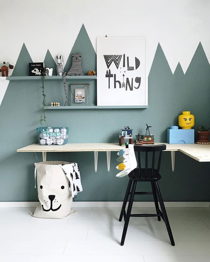 a room with mountains painted on the wall and shelves above it, along with toys