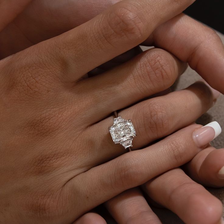 a woman's hand with a ring on her finger and a diamond in the middle