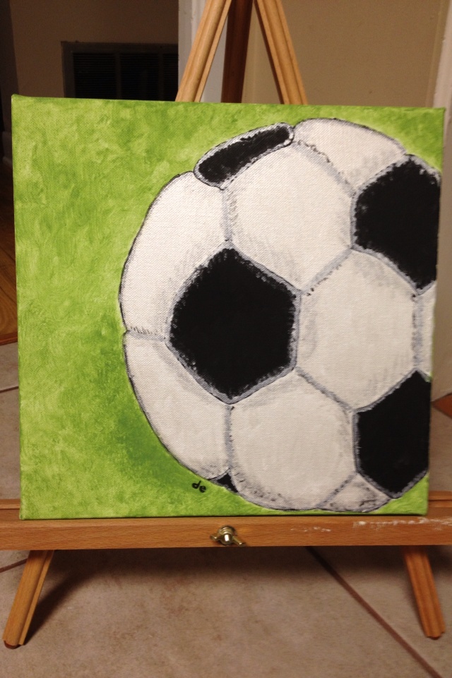 a painting of a black and white soccer ball on a green background with easel