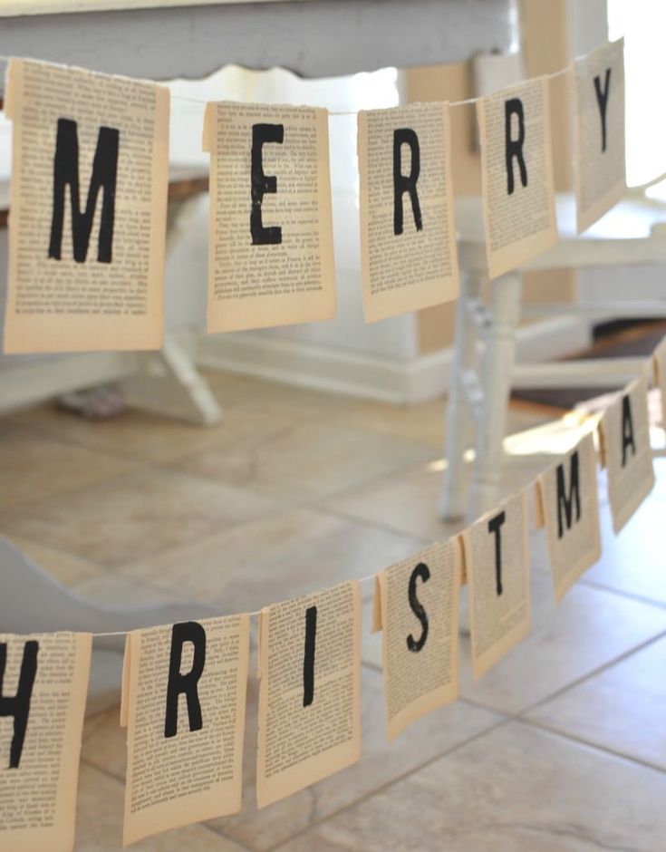 a merry christmas banner made out of old book pages hanging from a string on the floor