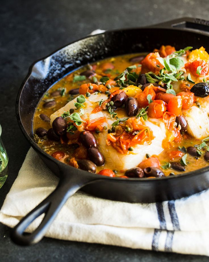 a skillet filled with fish and vegetables on top of a towel