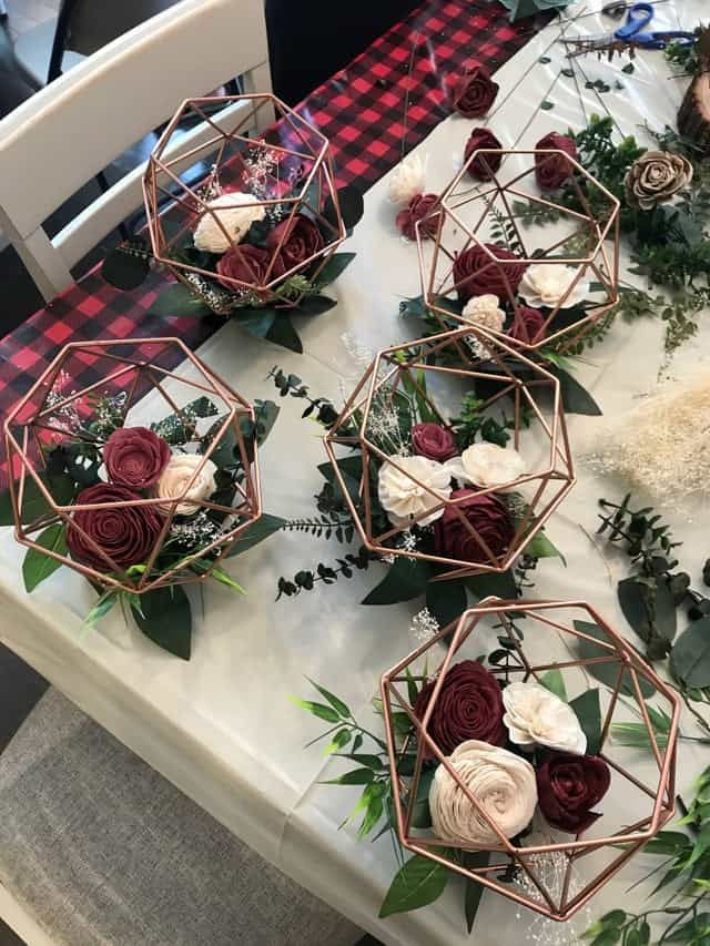 some flowers are sitting on a table with greenery and candles in the centerpieces