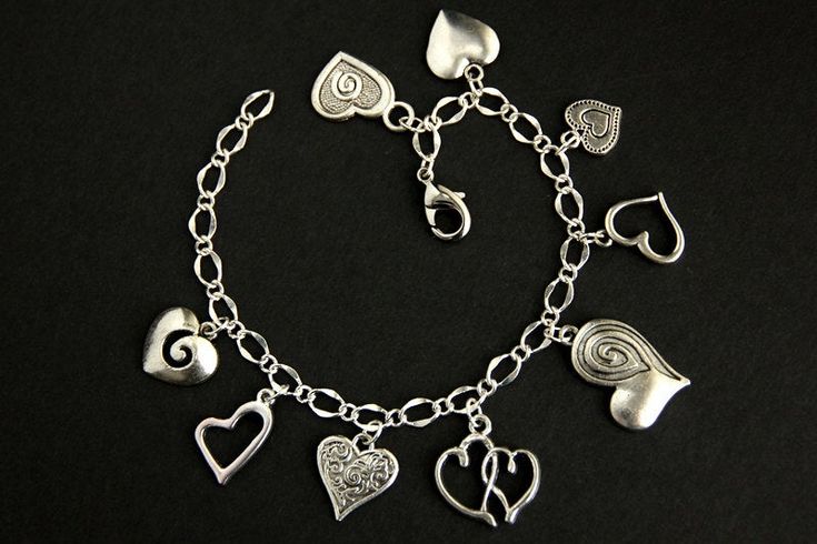 A collection of silver plated decorative heart charms have been dispersed around a shimmering silver plated bracelet chain in this handmade charm bracelet. This heart charm bracelet is then completed with a lobster clasp and a 1/2 inch of chain at the end for adjustable sizing. Charms in this bracelet include an assortment of nine decorative heart charms. ● Sizing ● To determine your bracelet size, do a snug measurement of your wrist's circumference, then add 1/2 an inch. 6 to 6.5 inches (15cm - Adjustable Silver Double Heart Charm Bracelet, Silver Adjustable Double Heart Charm Bracelet, Elegant Handmade Metal Heart Bracelet, Silver Metal Heart Bracelet With Charms, Silver Double Heart Metal Bracelet, Silver Metal Double Heart Bracelet, Silver Double Heart Charm Bracelet For Valentine's Day, Silver Heart Bracelet With Charms For Anniversary, Silver Heart Charm Dangle Bracelet