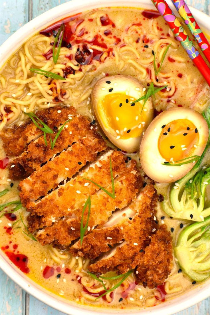 a bowl filled with noodles, meat and boiled eggs on top of it next to chopsticks