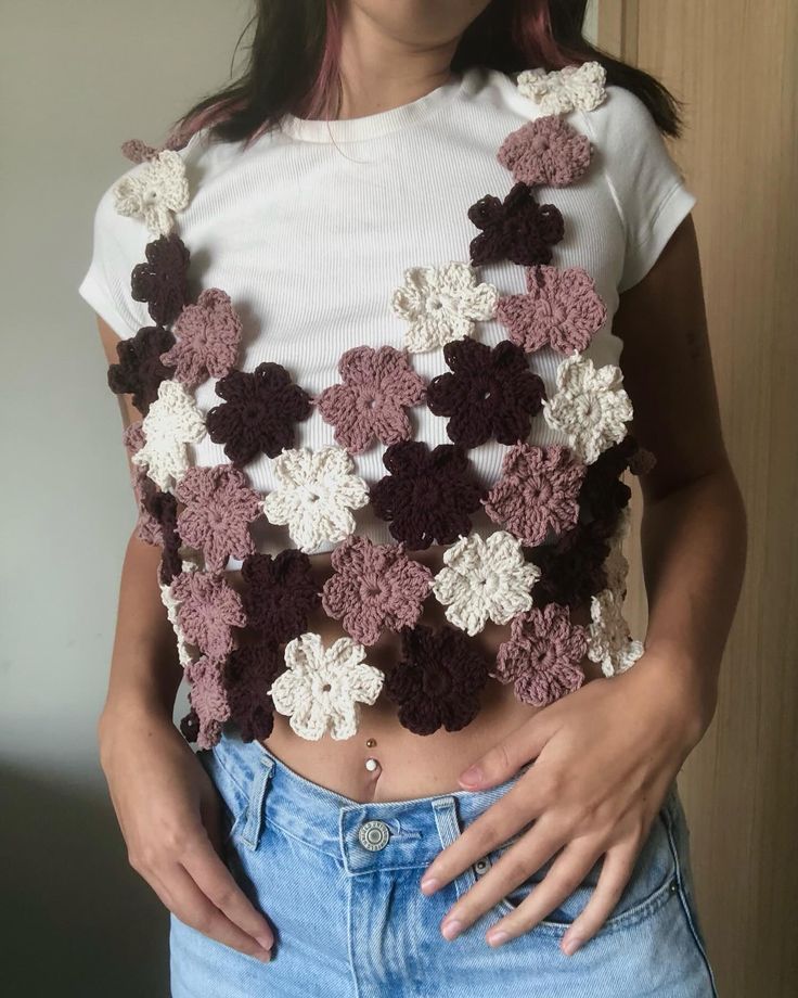 a woman is wearing a crocheted top with flowers on it