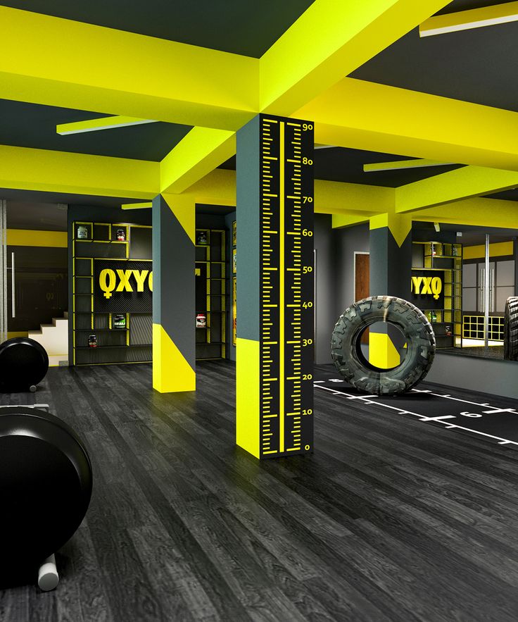 an empty gym with yellow and grey walls, black flooring and exercise equipment in the foreground