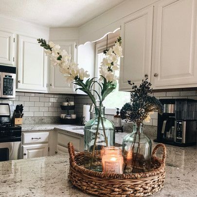 two vases filled with flowers on top of a kitchen counter