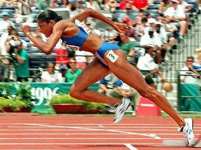 a woman running on a track in front of a crowd