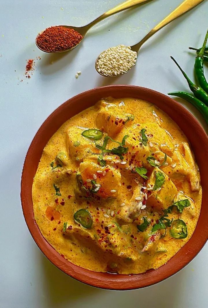 a bowl filled with yellow food next to some green beans and other ingredients on a white surface