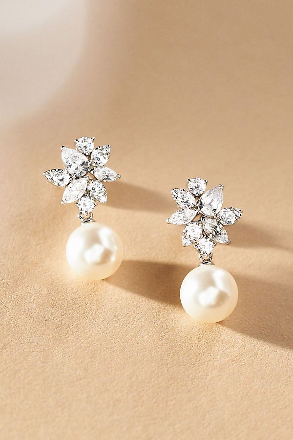 pair of pearl and crystal flower earrings on beige background with copy - space for text