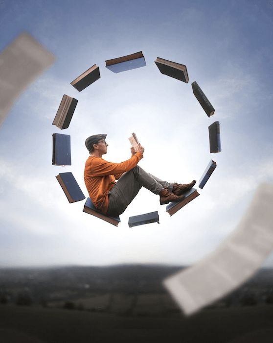 a man sitting on top of books flying through the air