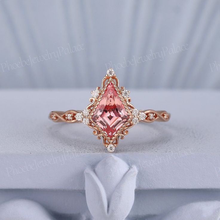 a pink diamond ring sitting on top of a white cloth