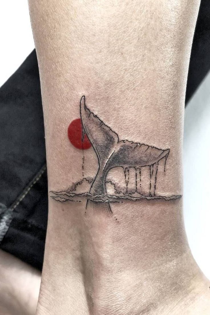 a tattoo on the ankle of a woman with a red dot in her left foot