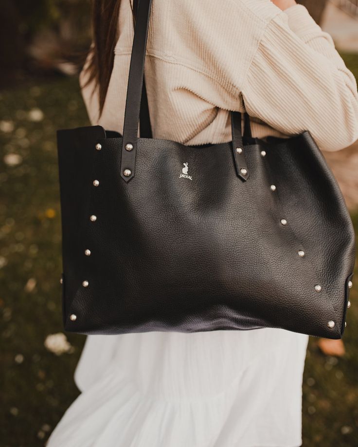 Introducing the studded tote! This unstructured bag is perfect for everyday use, featuring a spacious interior complete with an additional pocket with a snap closure. The riveted construction allows this bag to be robust and offers a unique design. Crafted with sturdy full-grain leather so you can have peace of mind that this bag can handle everyday use. 10oz vegetable tanned handles 4-5oz full-grain leather Solid brass rivets Foil embossed Jackal Logo Dimensions: 18"w x 10.5"h x 5"d Internal Po Daily Use Satchel Bag With Rivets, Daily Use Satchel With Rivets, Everyday Tote Bag With Rivets, Everyday Shoulder Bag With Rivets, Riveted Shoulder Bag, Everyday Studded Bags, Chic Shoulder Bag With Rivets For Everyday Use, Chic Everyday Shoulder Bag With Rivets, Rectangular Studded Shoulder Bag For Everyday Use