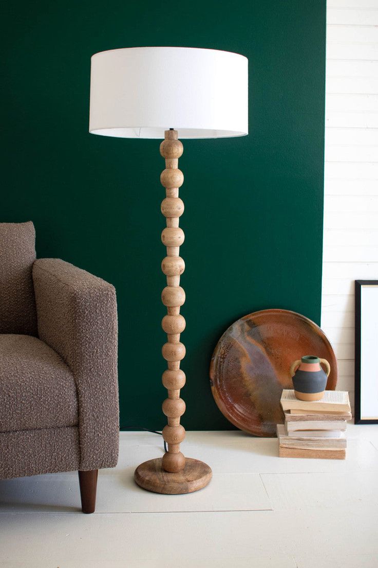 a living room with green walls and a lamp on the floor next to a chair