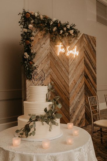 a wedding cake sitting on top of a table next to candles and a wooden wall