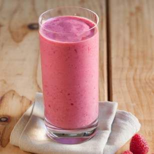 a pink smoothie with raspberries on a napkin next to it and two strawberries