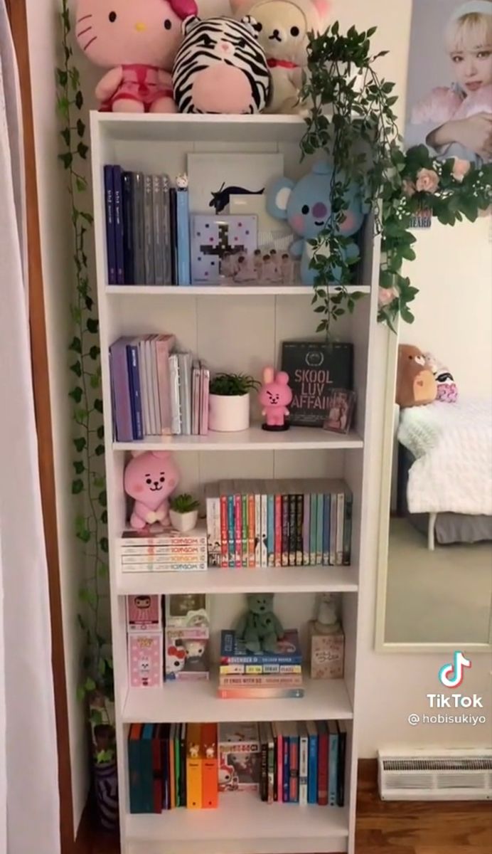 a book shelf filled with lots of books and stuffed animals next to a mirror on the wall