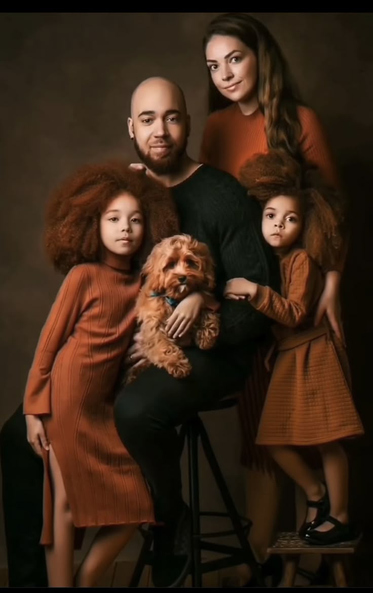 a family posing for a portrait with their dog and two children in front of them