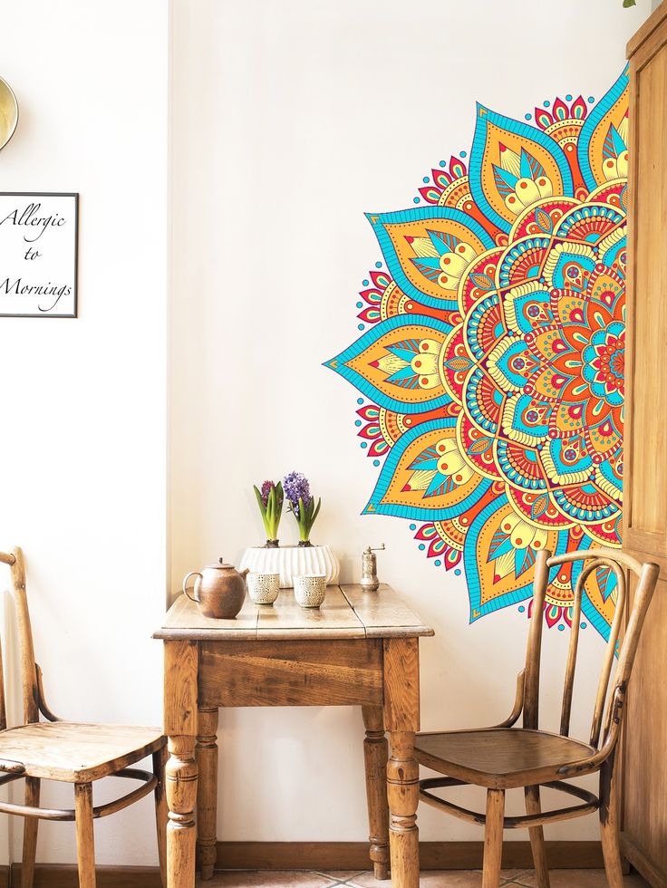 a room with two chairs and a table in front of a large colorful wall mural