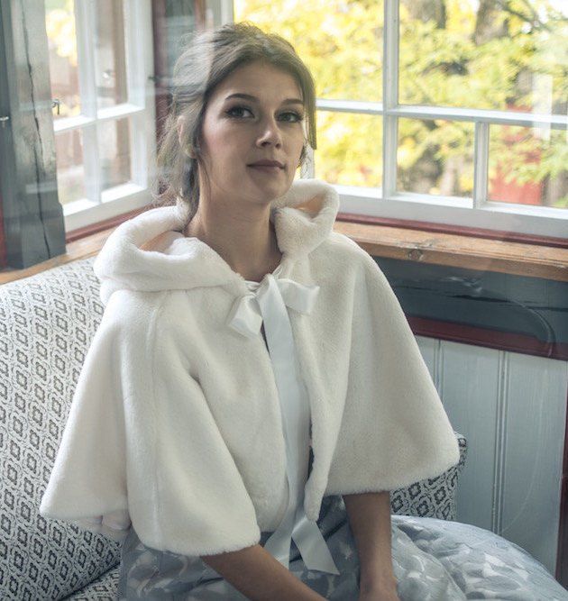 a woman sitting on a couch wearing a white coat