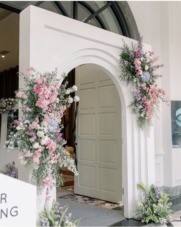 an archway with flowers and greenery on it