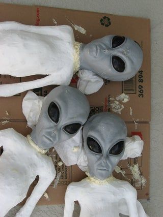 three fake alien heads sitting on top of a cardboard box