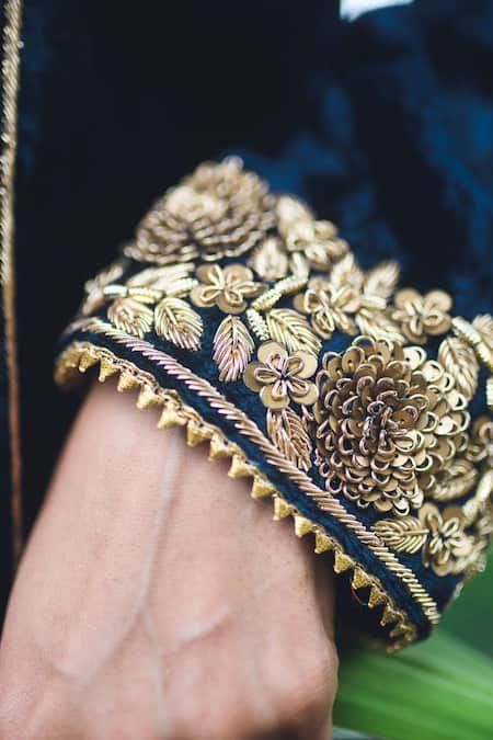 a close up of a person's hand wearing a gold and black bracelet with flowers on it