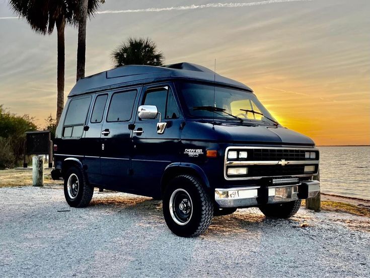 a van is parked on the side of the road near the water and palm trees