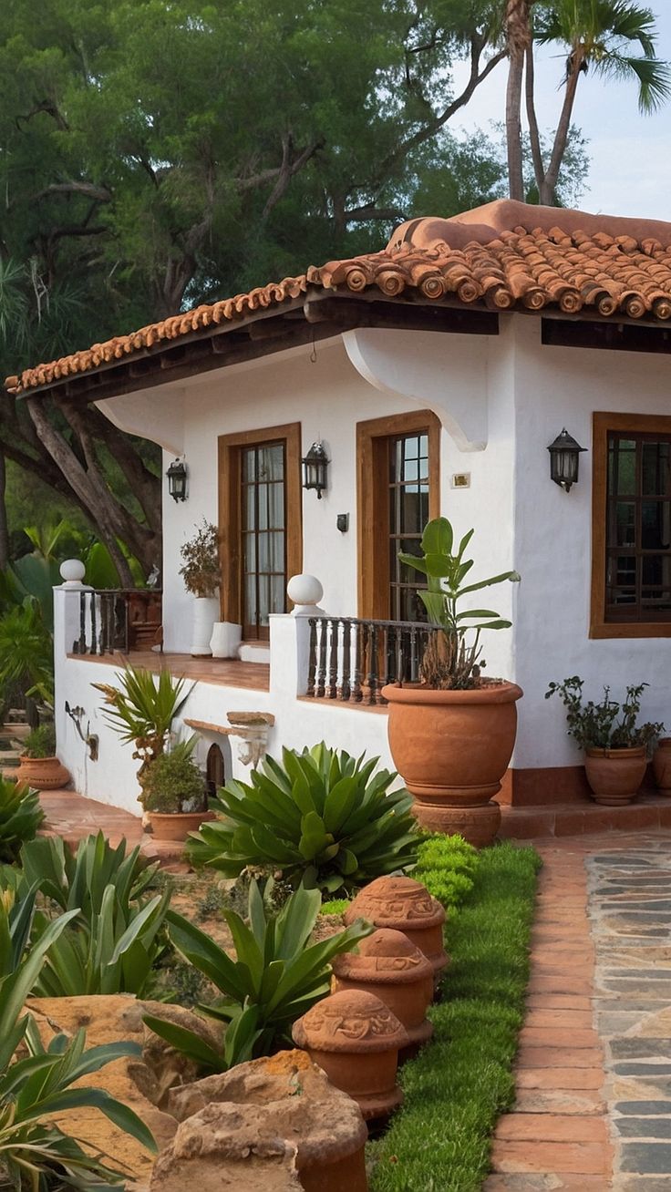 a small white house with potted plants in front