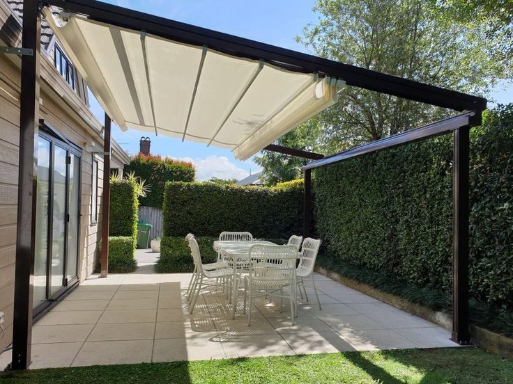 an outdoor patio with table and chairs under a white awning over the dining area