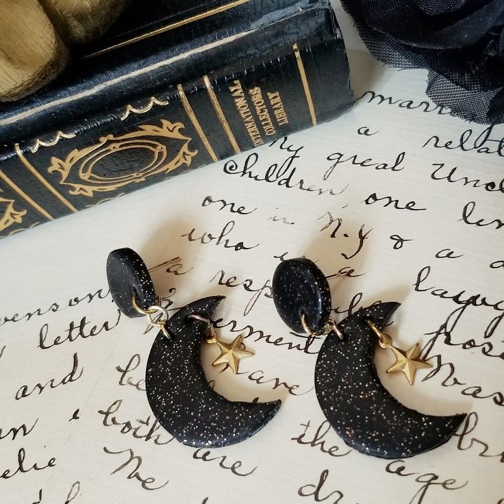 "CRESCENT MOON EARRINGS Inspired by the dark midnight sky with the crescent moon and the twinkling stars at night.  Beautiful black and glitter polymer clay crescent moon shaped earrings with circle shaped posts accented with goldtone vintage metal star charms and goldtone posts.  Perfect to wear to weddings, special occasions or everyday wear.  :) Length:  1 3/4\" Width:  3/8\" Thickness of Clay:  1/4\" MATERIALS:  Polymer Glitter Clay, Goldtone Jump Rings & Goldtone Nickel Free Posts Earrings, Celestial Halloween, Vintage Stars, Night Beautiful, Metal Star, Twinkling Stars, Crescent Moon Earrings, Midnight Sky, Metal Stars, Earrings Polymer Clay