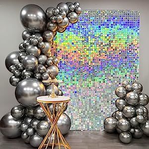 silver balloons are stacked on top of each other in front of an abstract painting and table