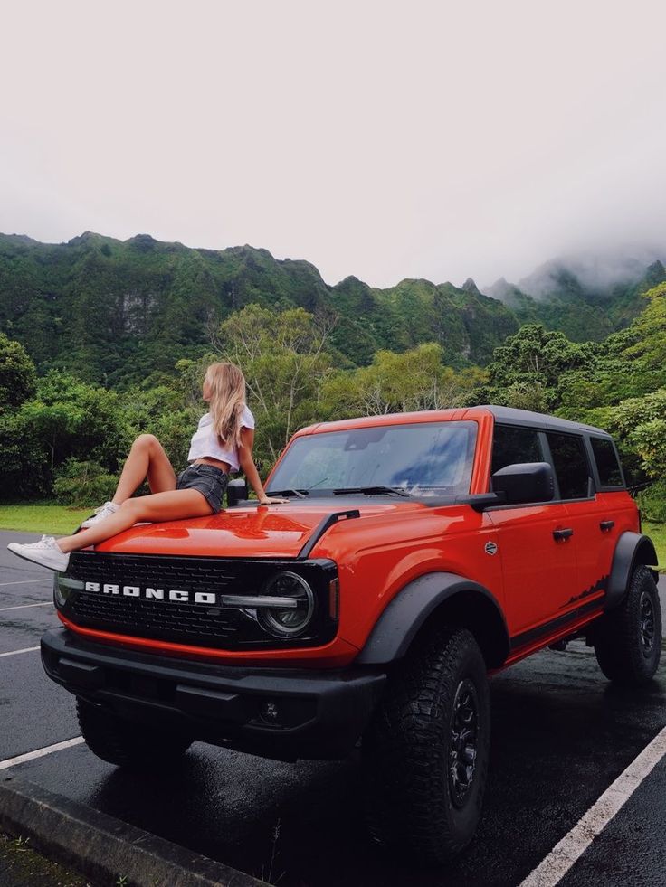 a woman sitting on the hood of a red truck