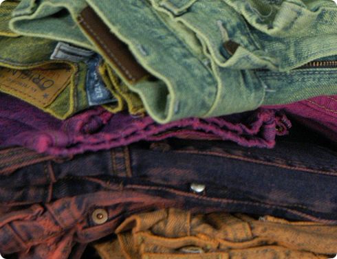 a pile of different colored jeans sitting on top of each other