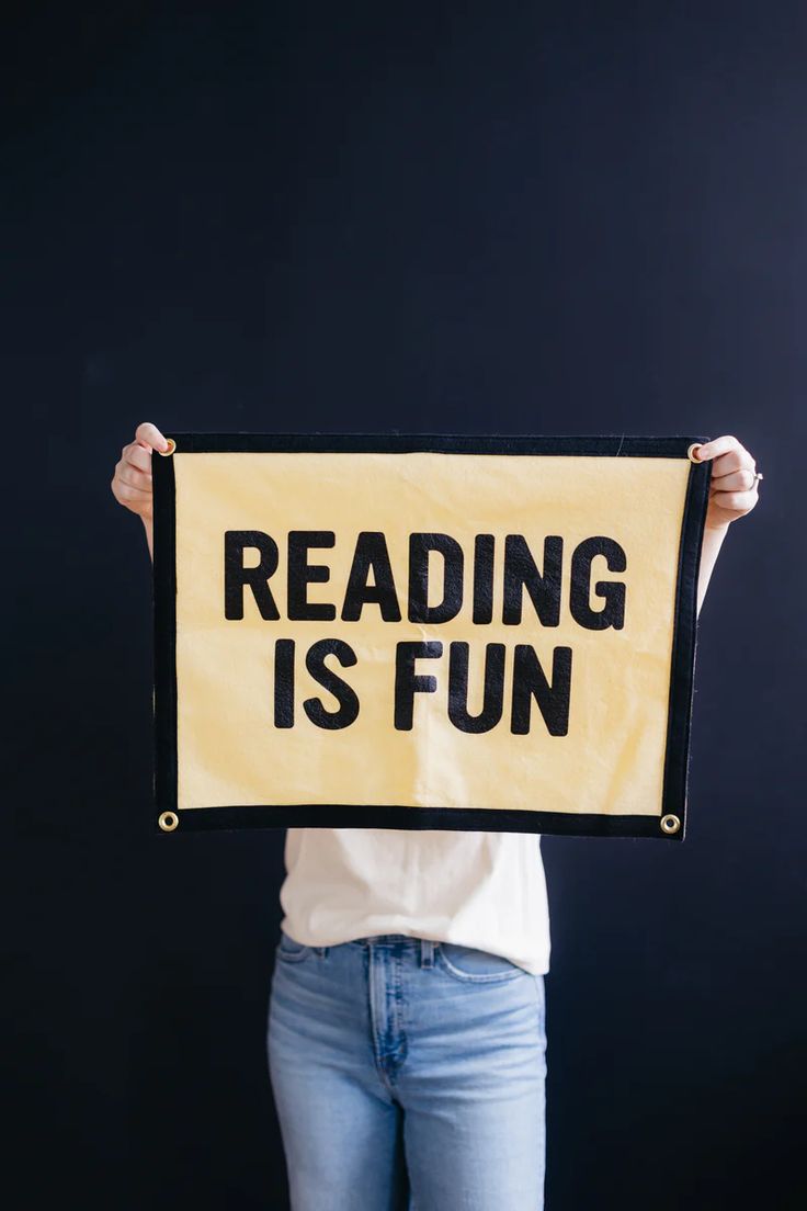 a woman holding up a reading is fun sign