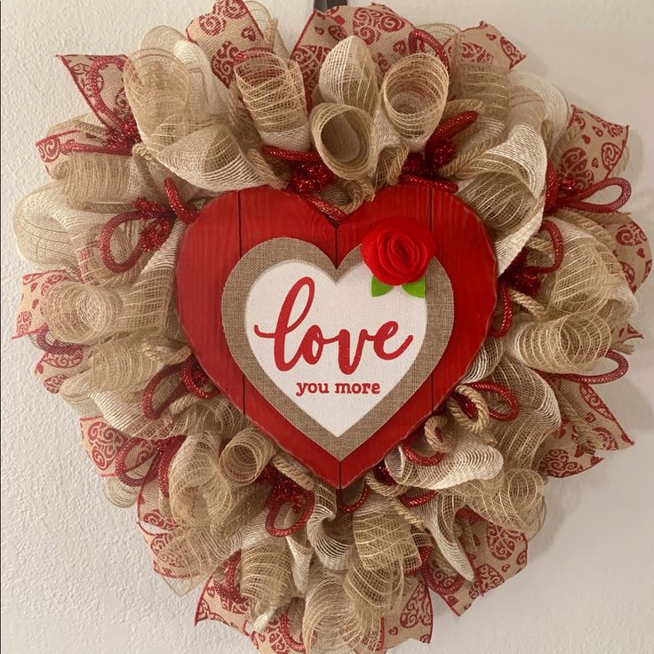 a heart shaped wreath with the words love you more on it hanging on a wall