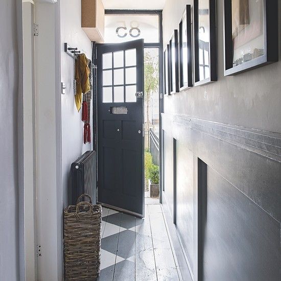 a hallway with pictures on the wall and a basket in front of an open door