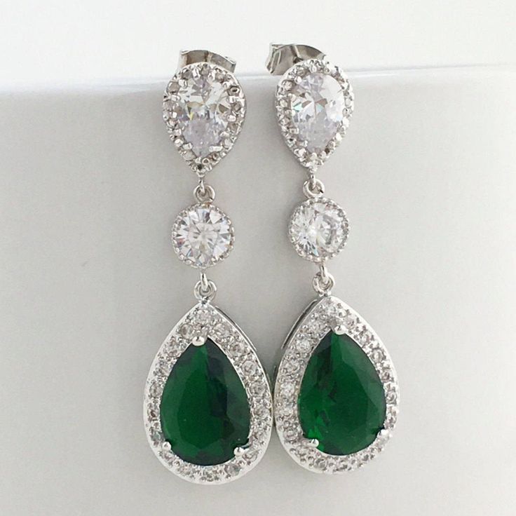 Luxury green emerald cubic zirconia bridal teardrop earrings in rhodium plated brass setting. Earrings feature a large teardrop with pear cut green emerald cubic zirconia center surrounded by tiny round zirconia crystals. Teardrop dangles from a clear cubic zirconia ear stud and a round cubic zirconia connector. Total length of the earring is 4.6 cms. Also available in clip on style. For matching necklace click: https://www.etsy.com/listing/481705468/green-emerald-cubic-zirconia-bridal?ref=listi Pear-shaped Emerald Earrings For Wedding, Green Cubic Zirconia Bridal Earrings, Teardrop Emerald Earrings For Wedding, Cubic Zirconia Teardrop Earrings For May Birthstone, Green Teardrop Cubic Zirconia Earrings, May Birthstone Teardrop Cubic Zirconia Earrings, Green Teardrop Bridal Earrings For Wedding, Wedding Drop Earrings With Emerald, Green Teardrop Wedding Earrings